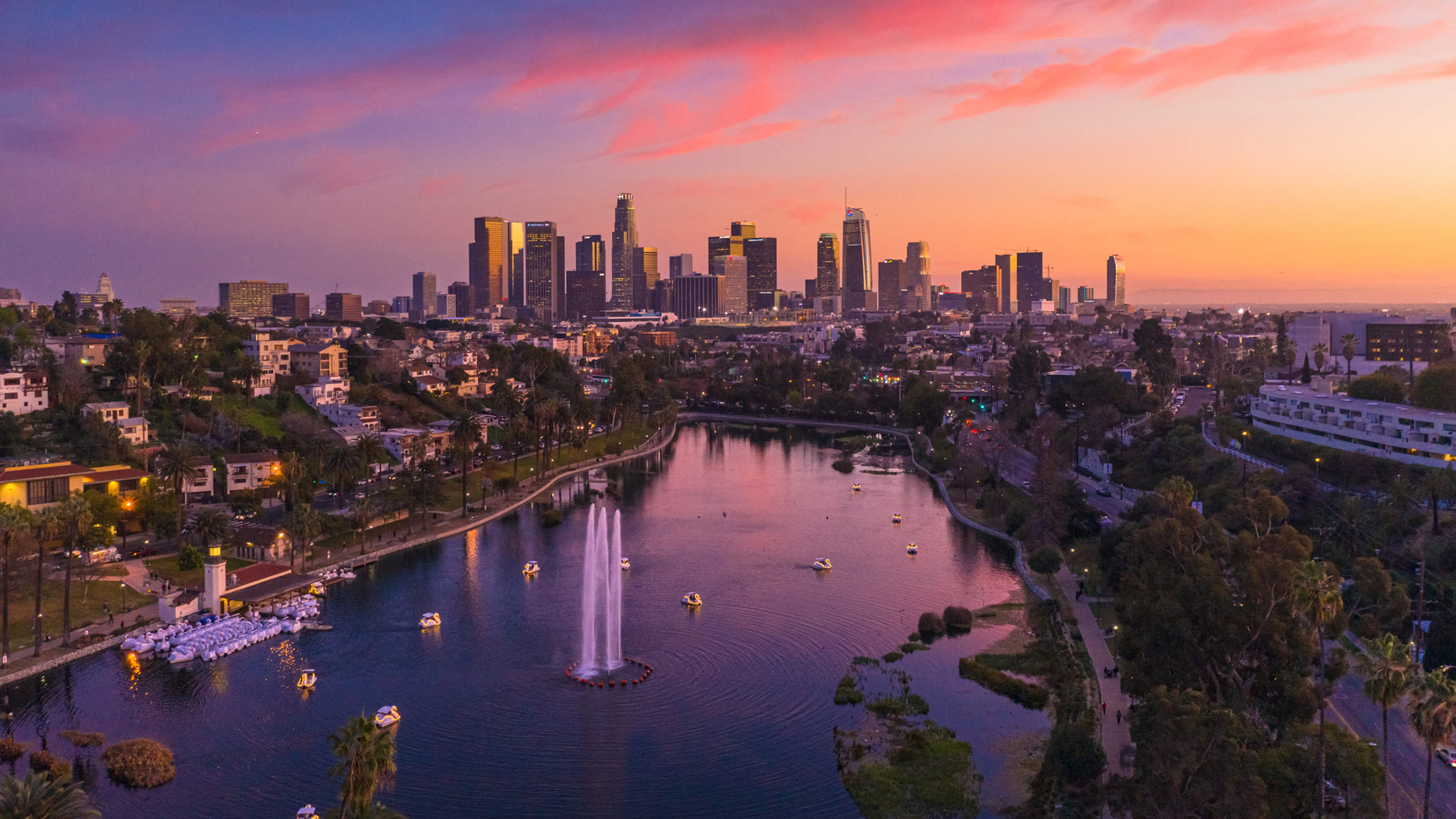 Vogelperspectief op de wolkenkrabbers van Los Angeles, met een park en een meer op de voorgrond.