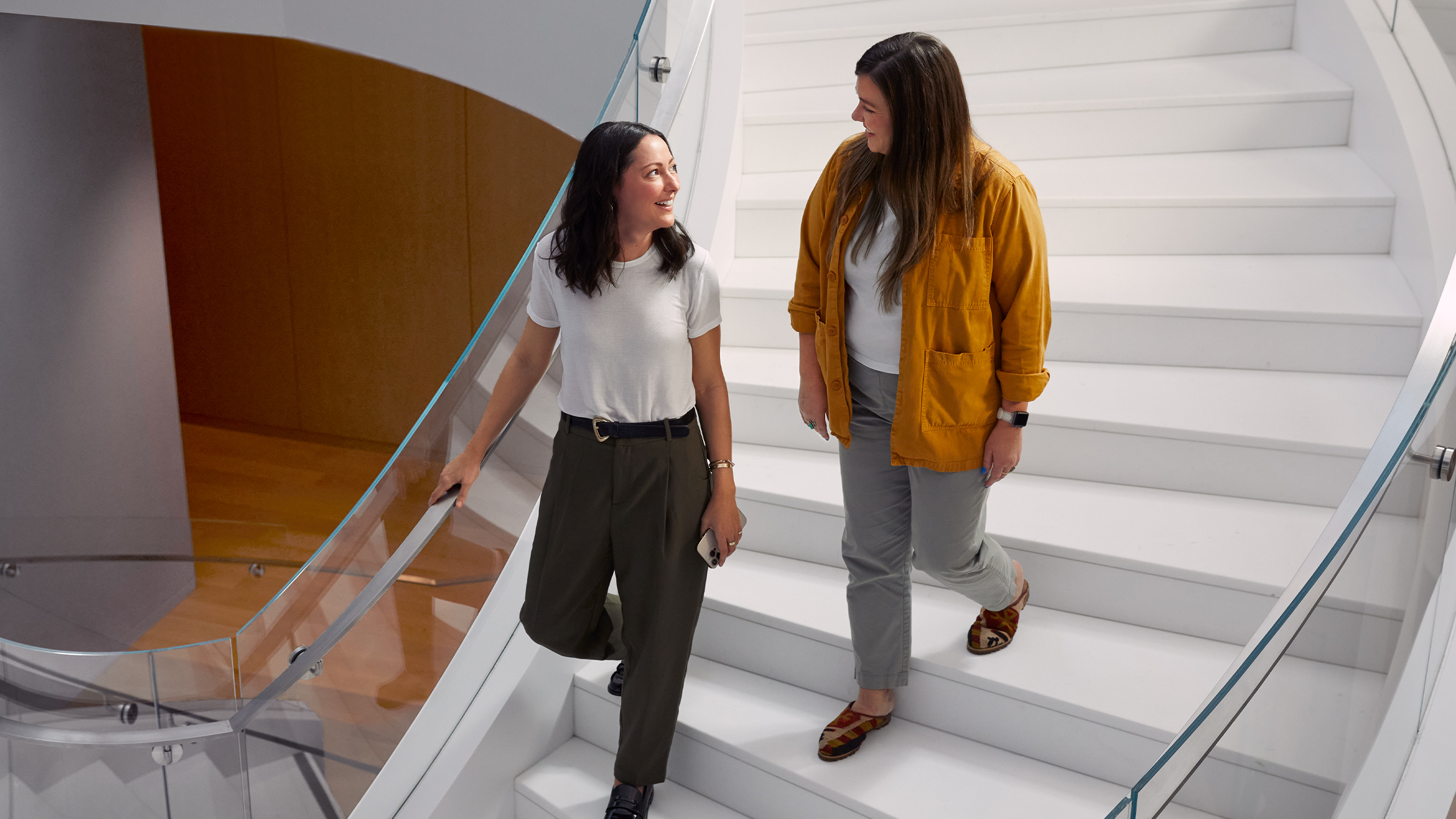 Twee Apple medewerkers wandelen een brede wenteltrap af. 