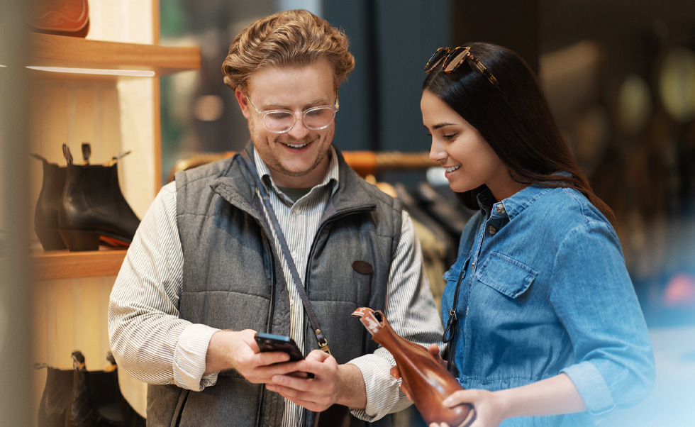 En salgsmedarbejder bruger iPhone i butikken til at hjælpe en kunde.